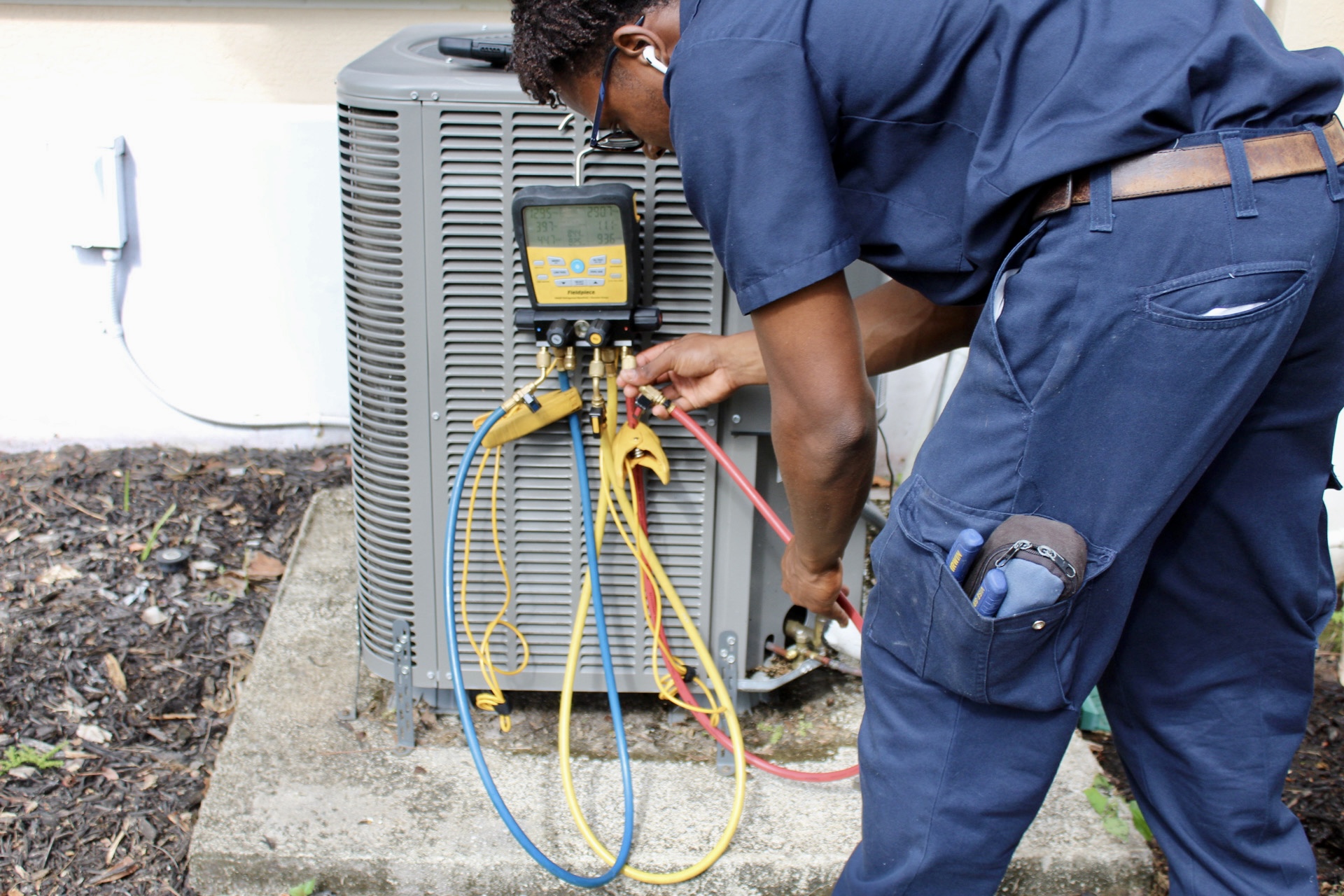 Technician servicing a central A/C condenser during maintenance