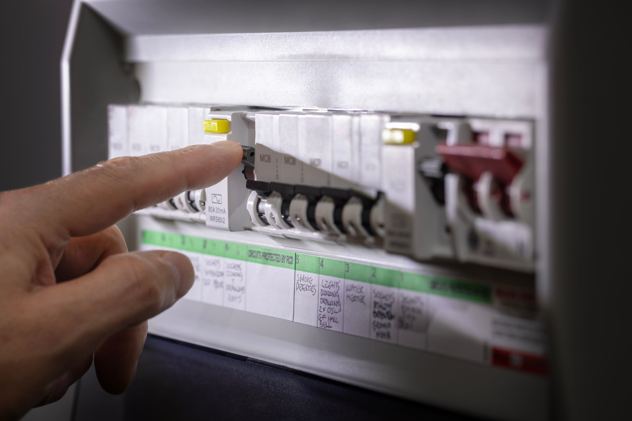 A hand resetting a residential circuit breaker after a power outage.