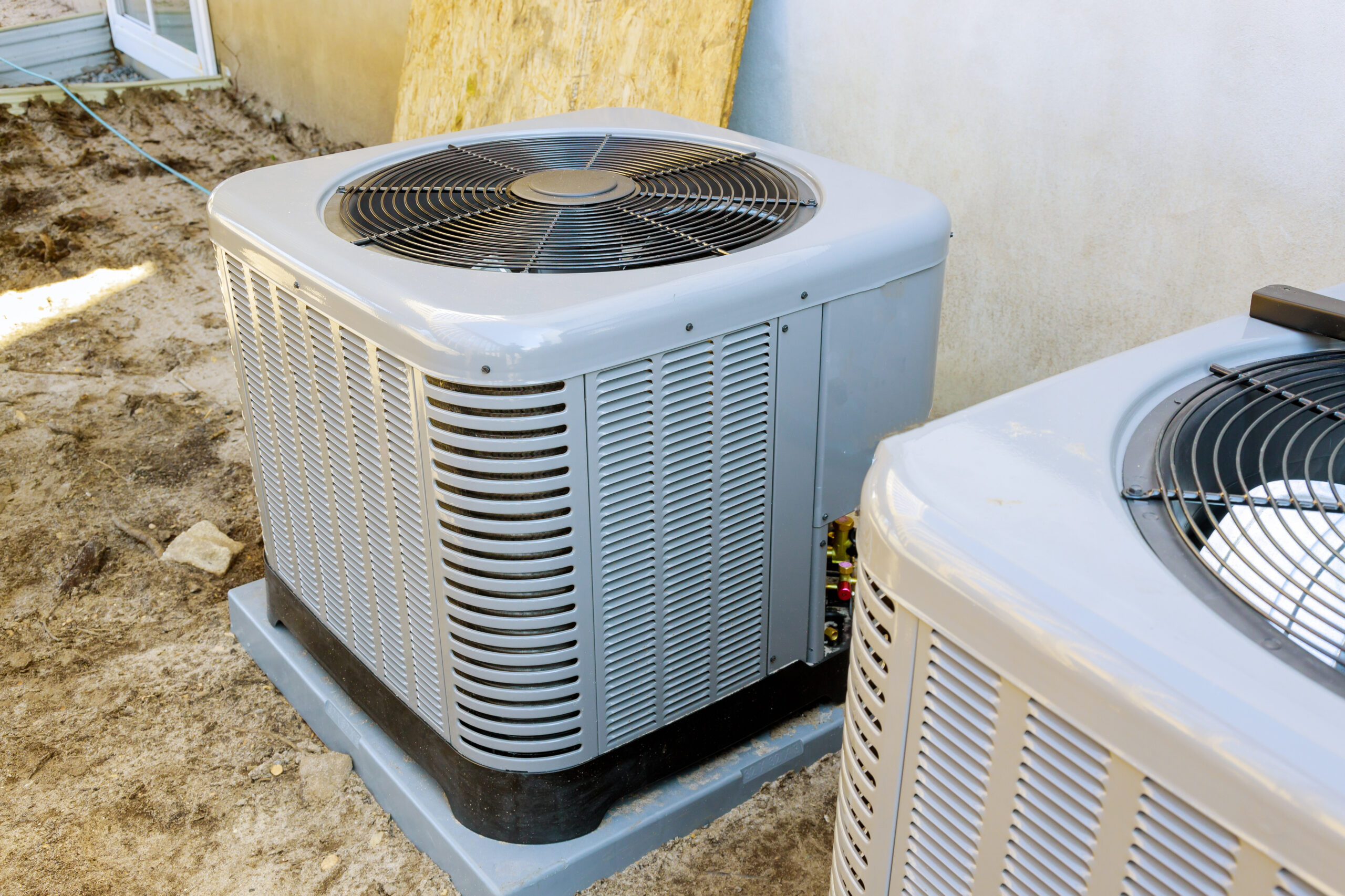 A residential central A/C outdoor condenser unit outside a Florida home with palm trees in the background, illustrating hurricane season preparation on the Treasure Coast.