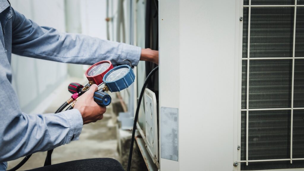 A/C technician using a manifold gauge to check refrigerant on an outdoor central air conditioning unit, the kind of service work an Honest Air comfort technician does across the Treasure Coast.